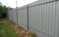 Забор из профнастила, столбы укреплены с помощью трамбовки грунта.
