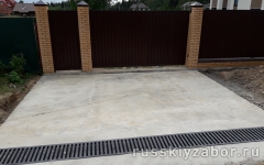 Площадка из бетона при въезде на участок с бетонированием дренажного русла, защищенного декоративной металлической решеткой