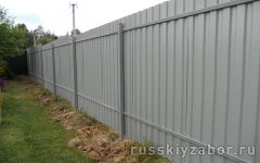 Забор из профнастила, столбы укреплены с помощью трамбовки грунта.